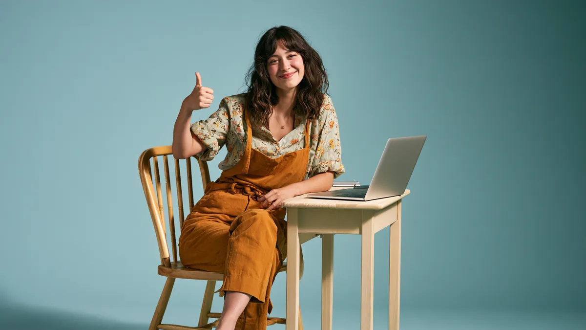 Woman at a laptop giving a cheerful thumbs up after submitting a Happy Money loan request — Happy Money personal loans.
